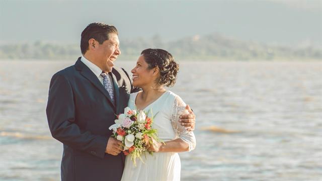 Novios abrazados frente a un lago