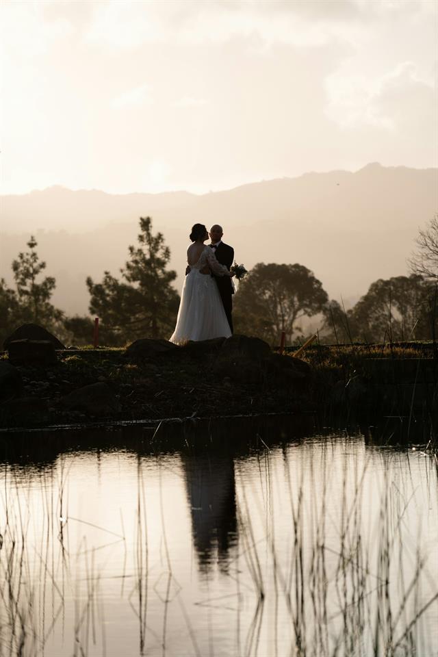 Novios en la orilla de una laguna al atardecer