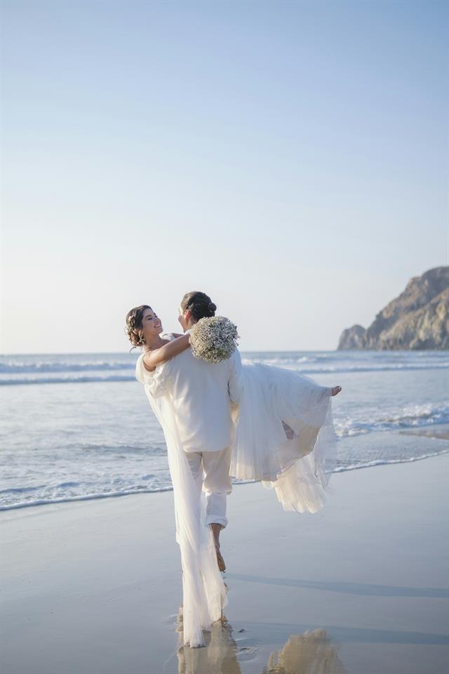 Novios en la playa con velo al viento