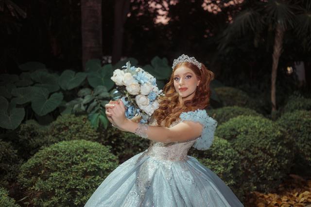 Quinceañera con vestido azul y ramo de flores