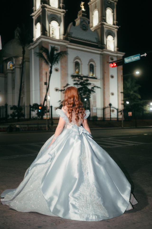 Quinceañera con vestido blanco frente a una iglesia