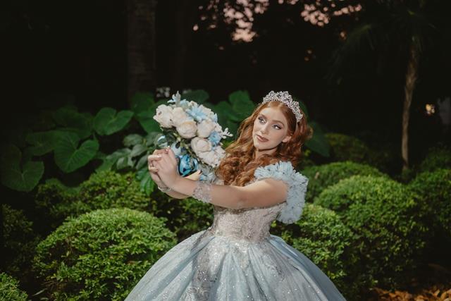 Quinceañera con vestido azul en un jardín